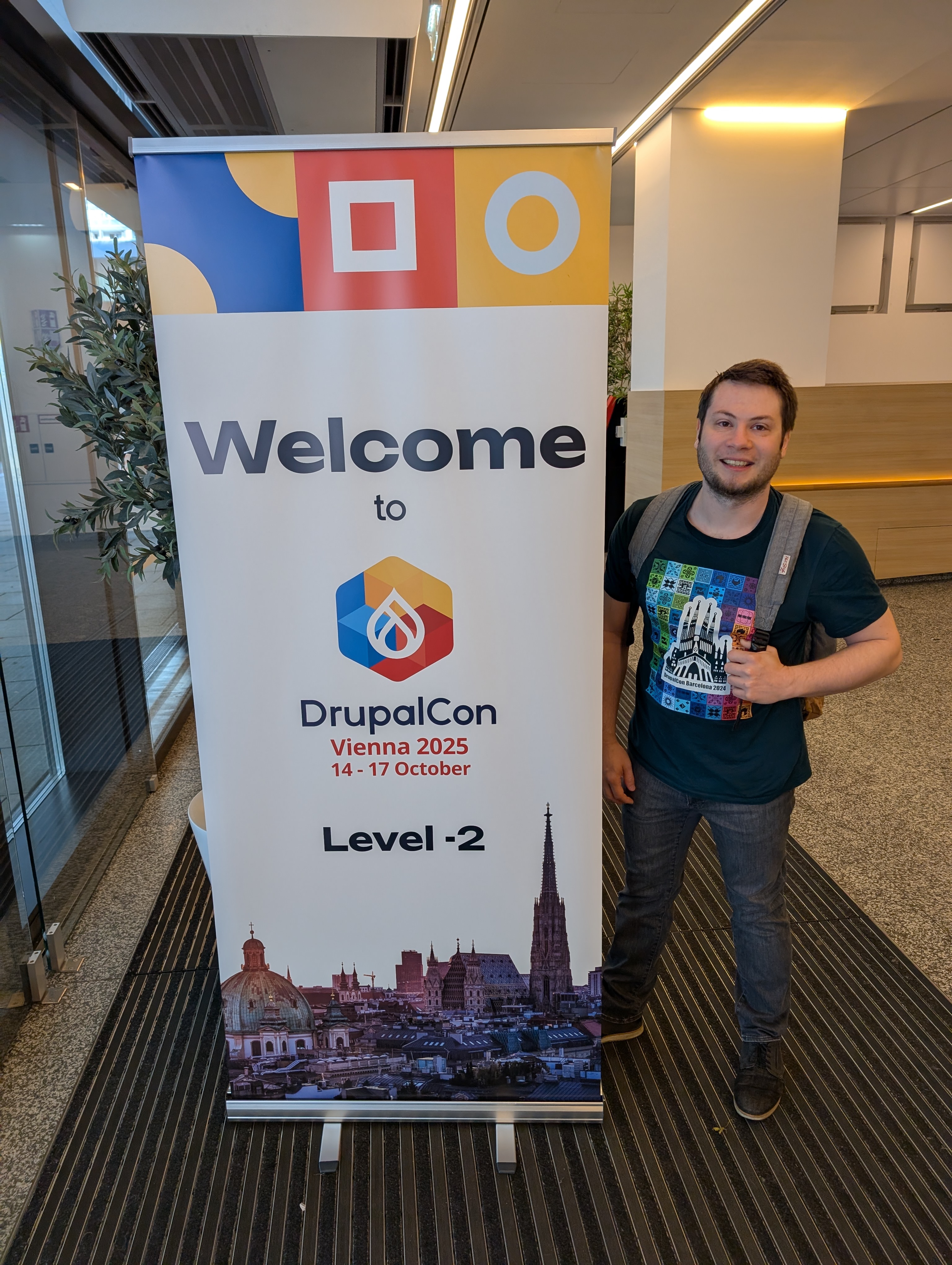Henjo steht neben Willkommensbanner zur DrupalCon 2025 Wien