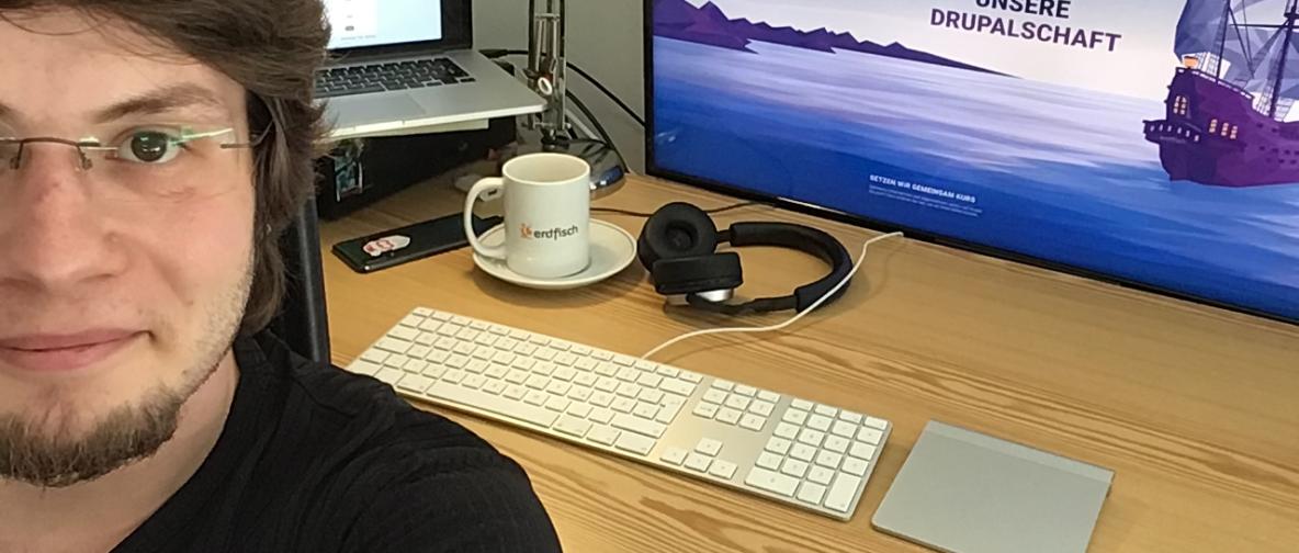 Mann vor Monitoren im Homeoffice in Selfie Position