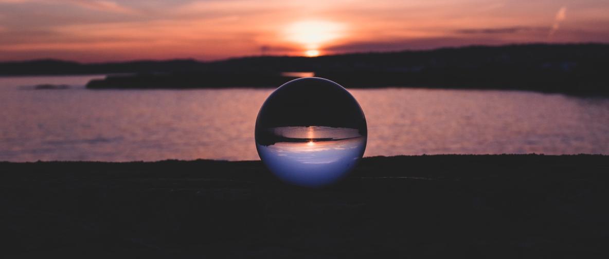 Kristallkugel vor einem GewÀsser bei Sonnenuntergang