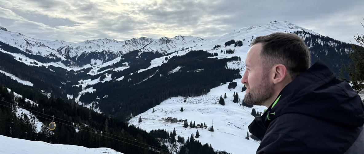 Person trinkt aus Tasse mit Blick auf schneebedeckte Berglandschaft.