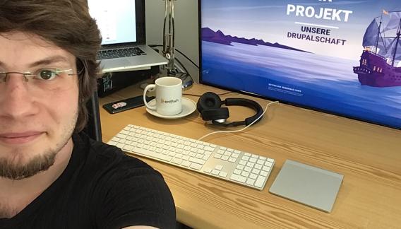 Mann vor Monitoren im Homeoffice in Selfie Position