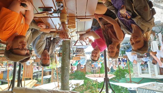 Eine Gruppe sitzt in einem Biergarten um einen Tisch.