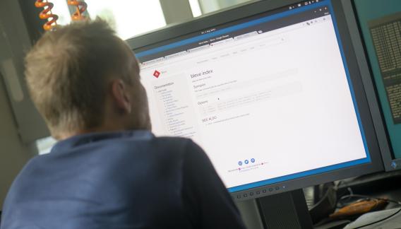erdfisch Mitarbeiter sitzt vor einem Computerbildschirm und liest die technische Dokumentation zu einer Software.